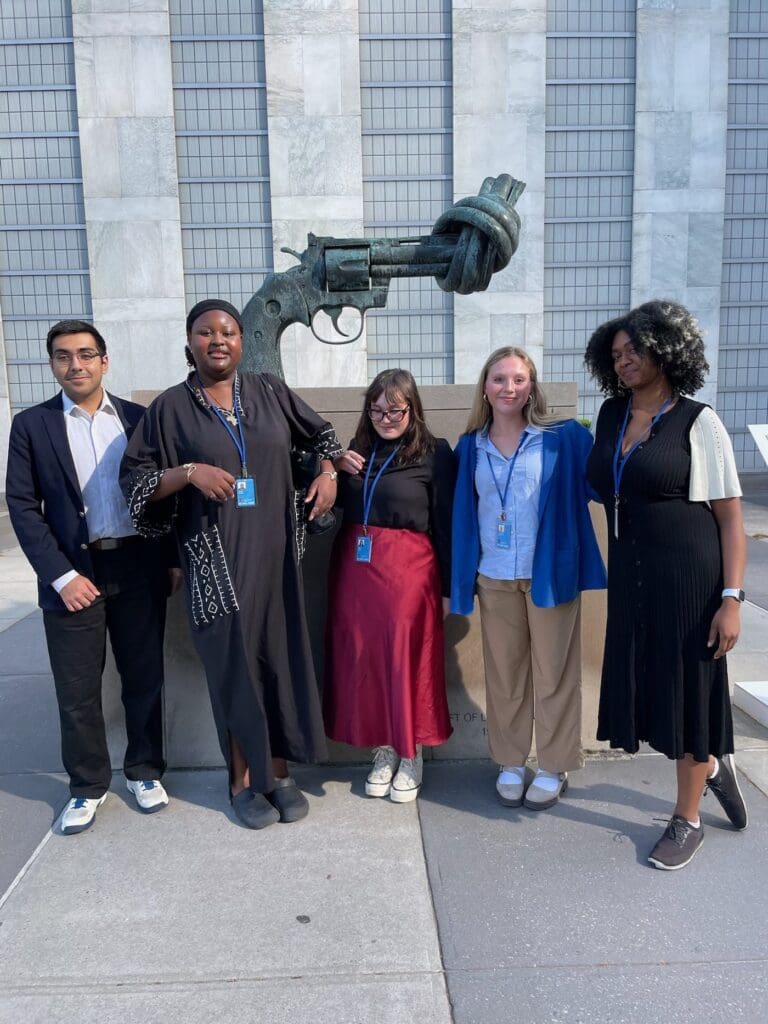 CGS youth advocates standing beside the Non-Violence knotted gun sculpture at United Nations Headquarters in New York.